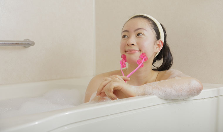 風呂で小顔ローラーを使用する女性