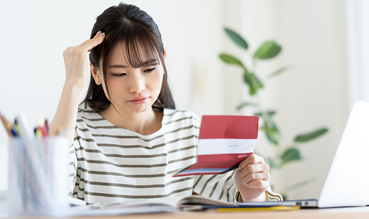 通帳を見て悩む女性