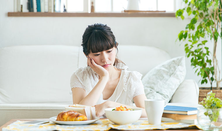 朝食を食べるかを悩む女性