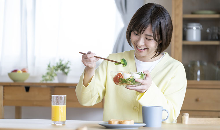 ブロッコリーサラダを食べる女性