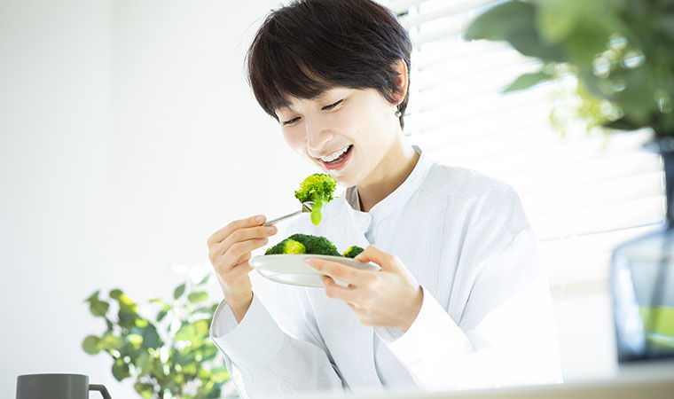 ブロッコリーを食べる女性